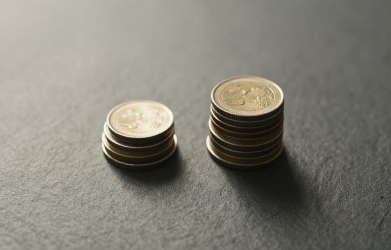Two uneven piles of coins on a slate surface, standing in for a partial refund that splits an order's value between the developer and the store
